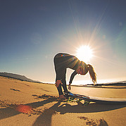Stretching-Session am Strand vor dem Einstieg ins Wasser.