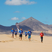 Surfschüler joggen am Strand von Fuerteventura zum Aufwärmen vor dem Surfkurs.