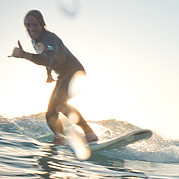 Glücklicher Surfer auf grüner Welle zeigt Hang Loose – surfen auf Fuerteventura