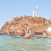 SUP Surflehrer hilft beim Aufstehen auf dem Brett SUP Surflehrer hilft beim Aufstehen auf dem Brett