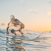 Surfer auf sauberer grüner Welle in Jandía bei Sonnenuntergang – surfen auf Fuerteventura