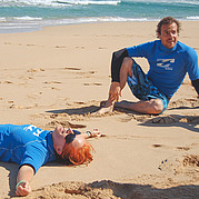 Zufriedener Surfschüler ruht sich am Strand nach einer intensiven Session aus.
